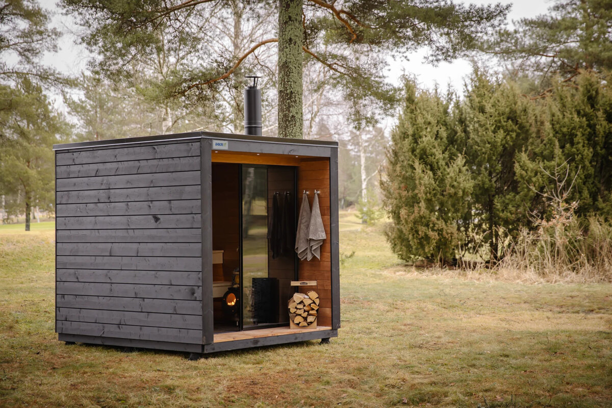 iHKA modular outdoor sauna in a forest setting with IKI wood-burning stove and snow-covered surroundings